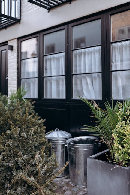A large glass window front of a restaurant or cafe, with white curtains covering the lower portion and warm interior lighting visible through the glass. The exterior features a black and grey facade w